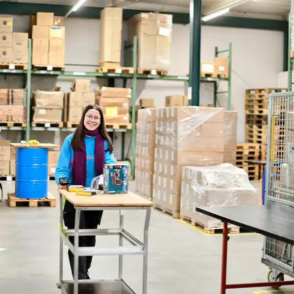 Junge Frau mit einem Rollwagen in einem Logistik Warenlager