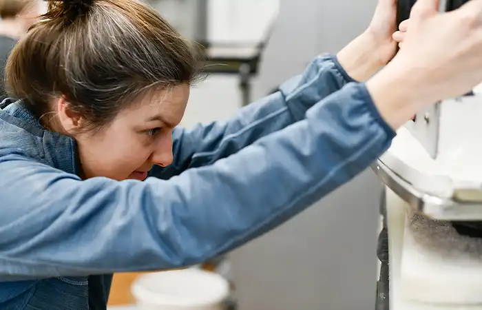Frau mit braunen Haaren arbeitet an einer Maschine