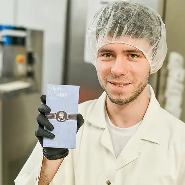 Junger Mann mit Haube präsentiert eine selbst hergestellte Schokolade