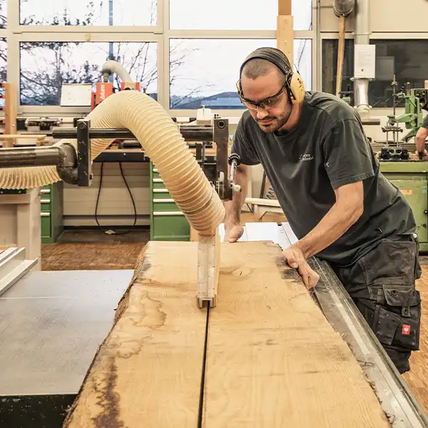 Mann arbeitet in der Schreinerei und sägt Holz