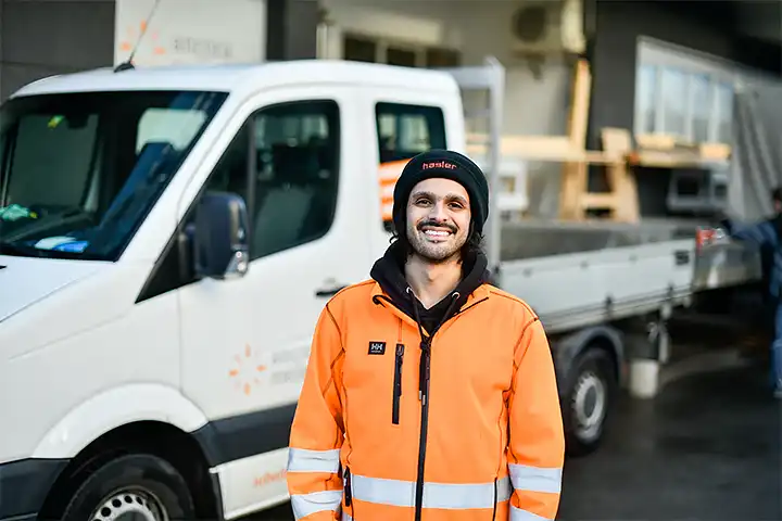Teamleiter mit Fahrzeug im Hintergrund, welches zur Hauswartung, Reinigung und Gartenpflege benötigt wird