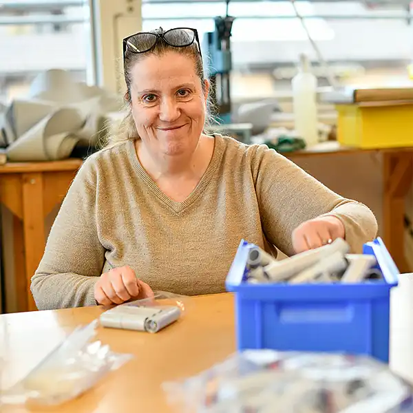 Frau mit Sonnenbrille auf dem Kopf arbeitet an einem Tisch und verpackt Rollen
