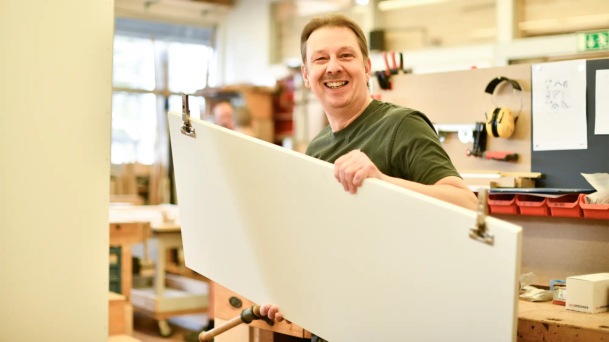 Mann lacht freundlich und arbeitet in der Schreinerei
