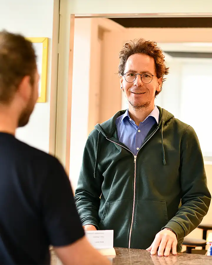 Mann schaut freundlich und bedient Kunden am Office-Schalter