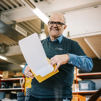 Mann mit Brille faltet eine Kartonschachtel
